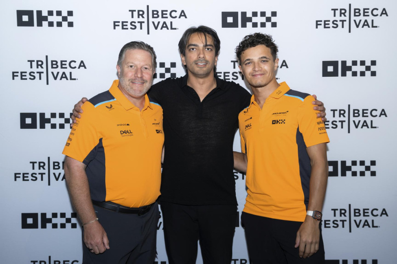 McLaren Racing CEO Zak Brown (in orange, left) and McLaren F1 Driver Lando Norris (in orange, right) with OKX CMO Haider Rafique